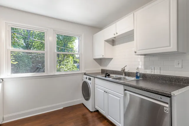 a kitchen with stainless steel appliances granite countertop white cabinets a sink a stove a window and a counter top space