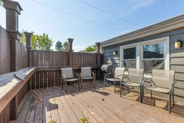 a view of a roof deck with table and chairs a barbeque with wooden floor and fence