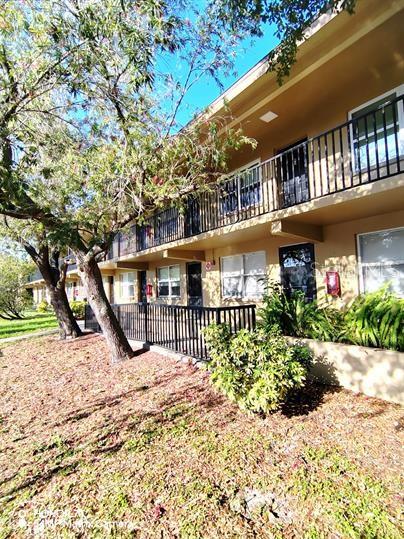 a view of a house with a wooden deck and a large tree