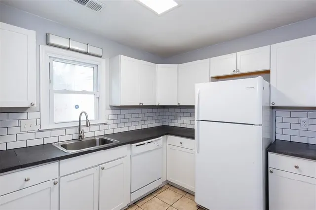 a white kitchen with sink and refrigerator