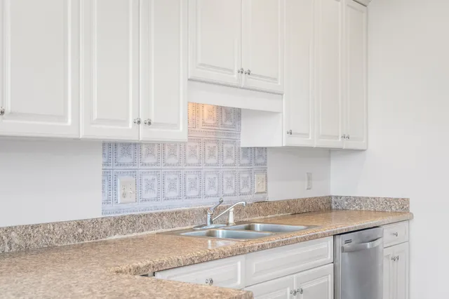 a kitchen with granite countertop white cabinets and a sink