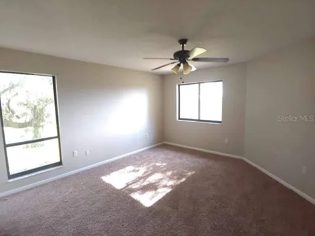 a view of empty room with windows and a ceiling fan