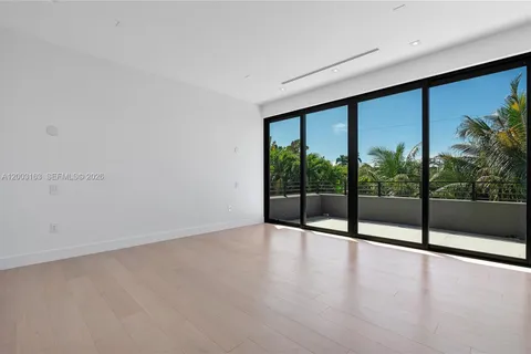 a view of an empty room with wooden floor and windows
