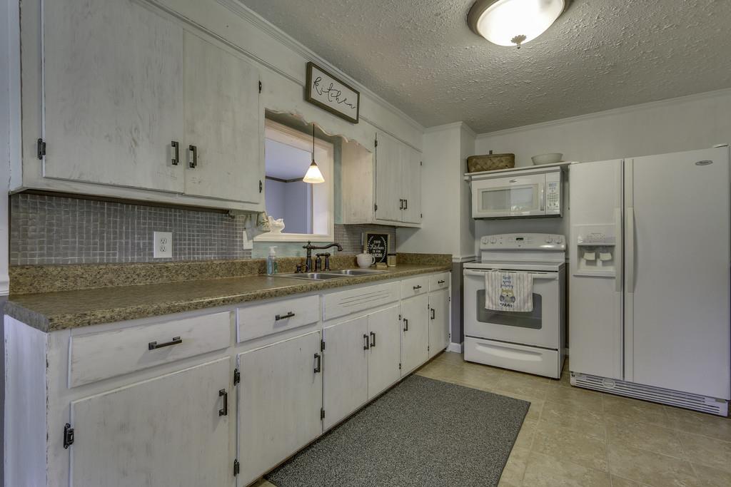 301 Whitson Road Bethpage, TN 37022 - Photo 13 of 29 a kitchen with granite countertop white cabinets and white appliances