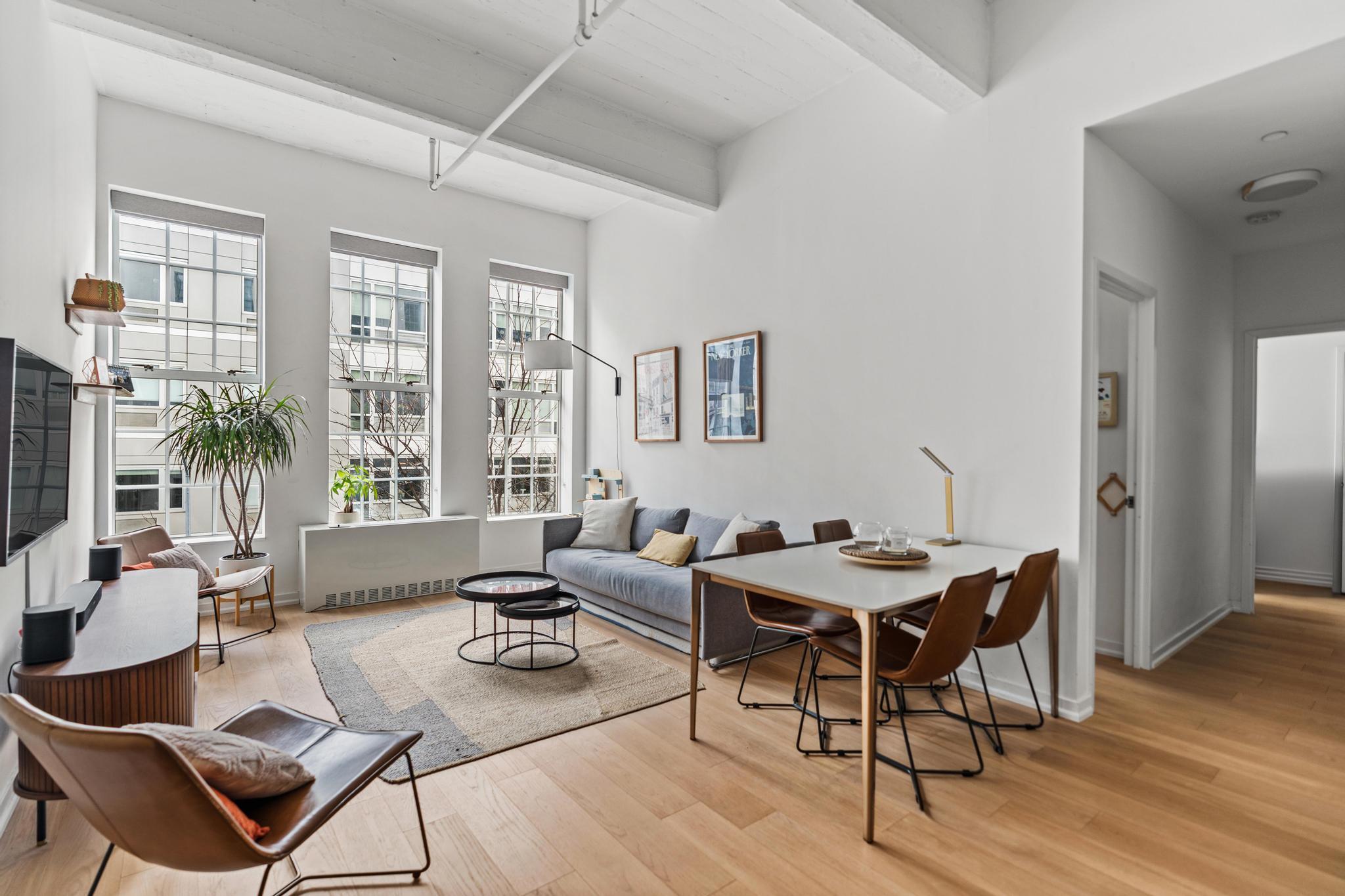 a living room with furniture a wooden floor and floor to ceiling window