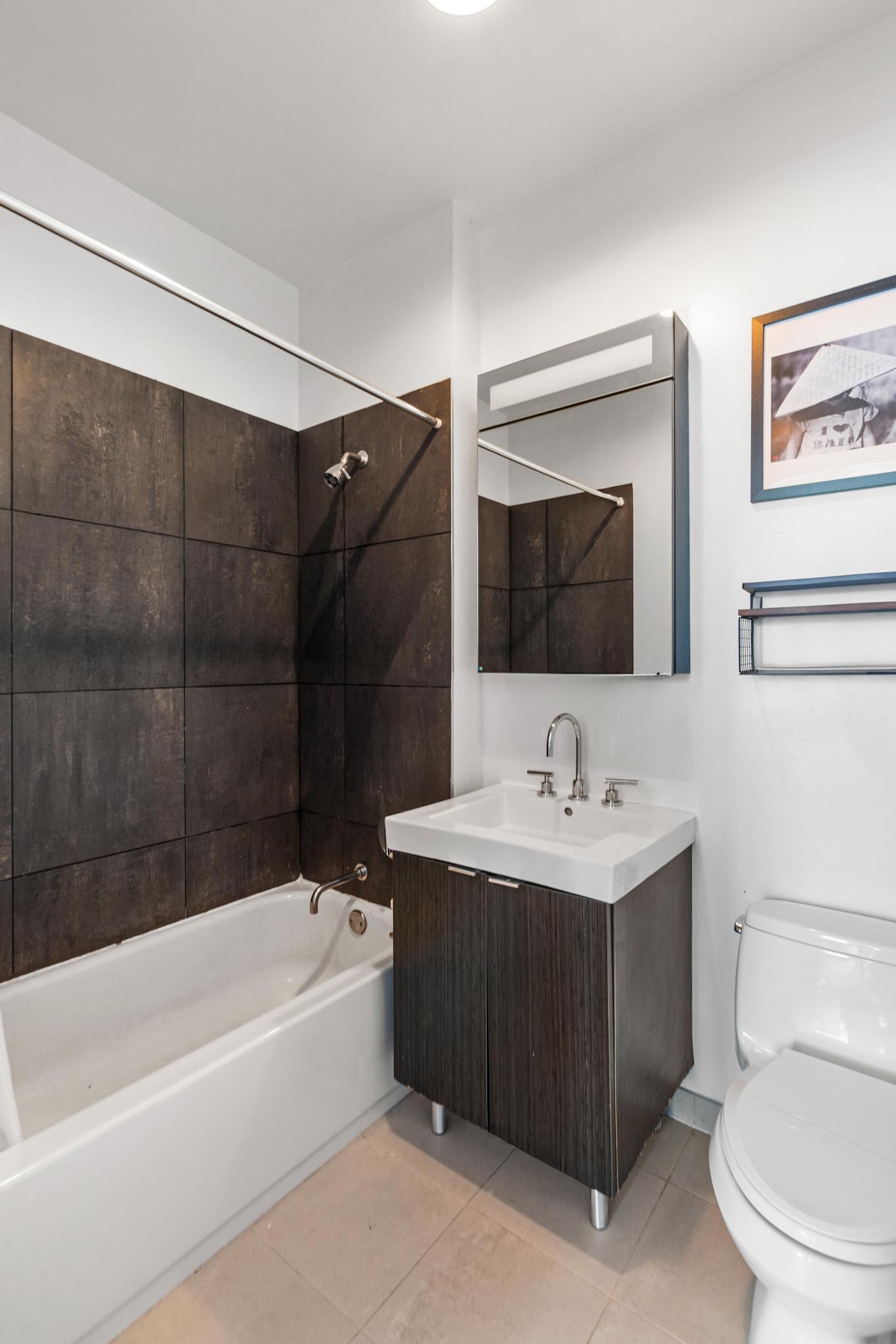 184 Kent Avenue, Unit D319 Brooklyn, NY 11249 - Photo 5 of 14 a bathroom with a sink a toilet and shower