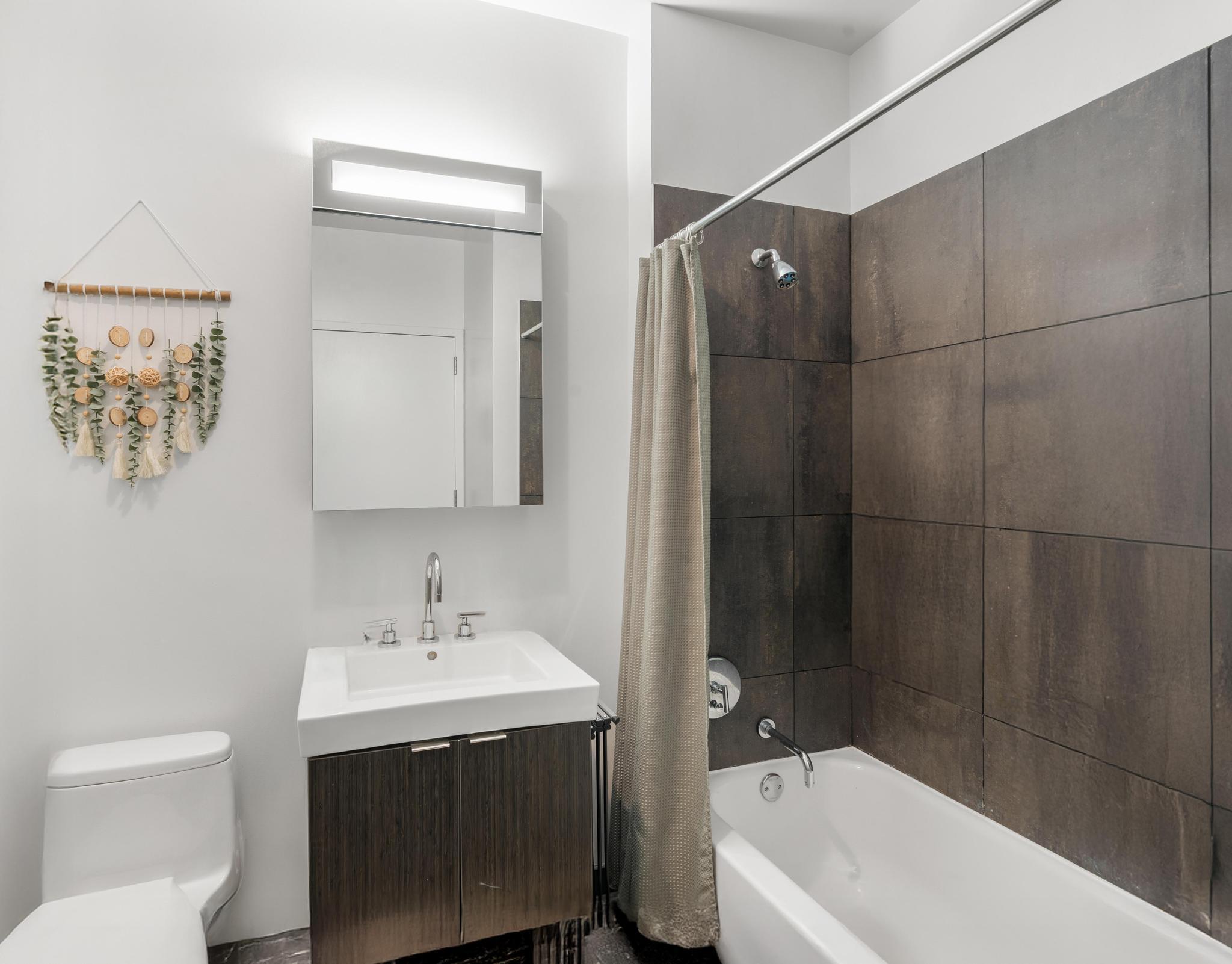 184 Kent Avenue, Unit D319 Brooklyn, NY 11249 - Photo 6 of 14 a bathroom with a sink toilet and shower