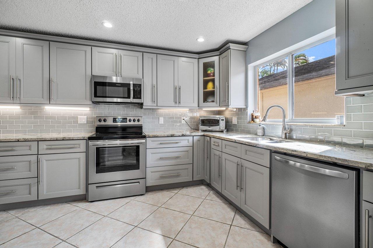 9155 Pine Springs Drive Boca Raton, FL 33428 - Photo 14 of 24 a kitchen with cabinets appliances and a sink