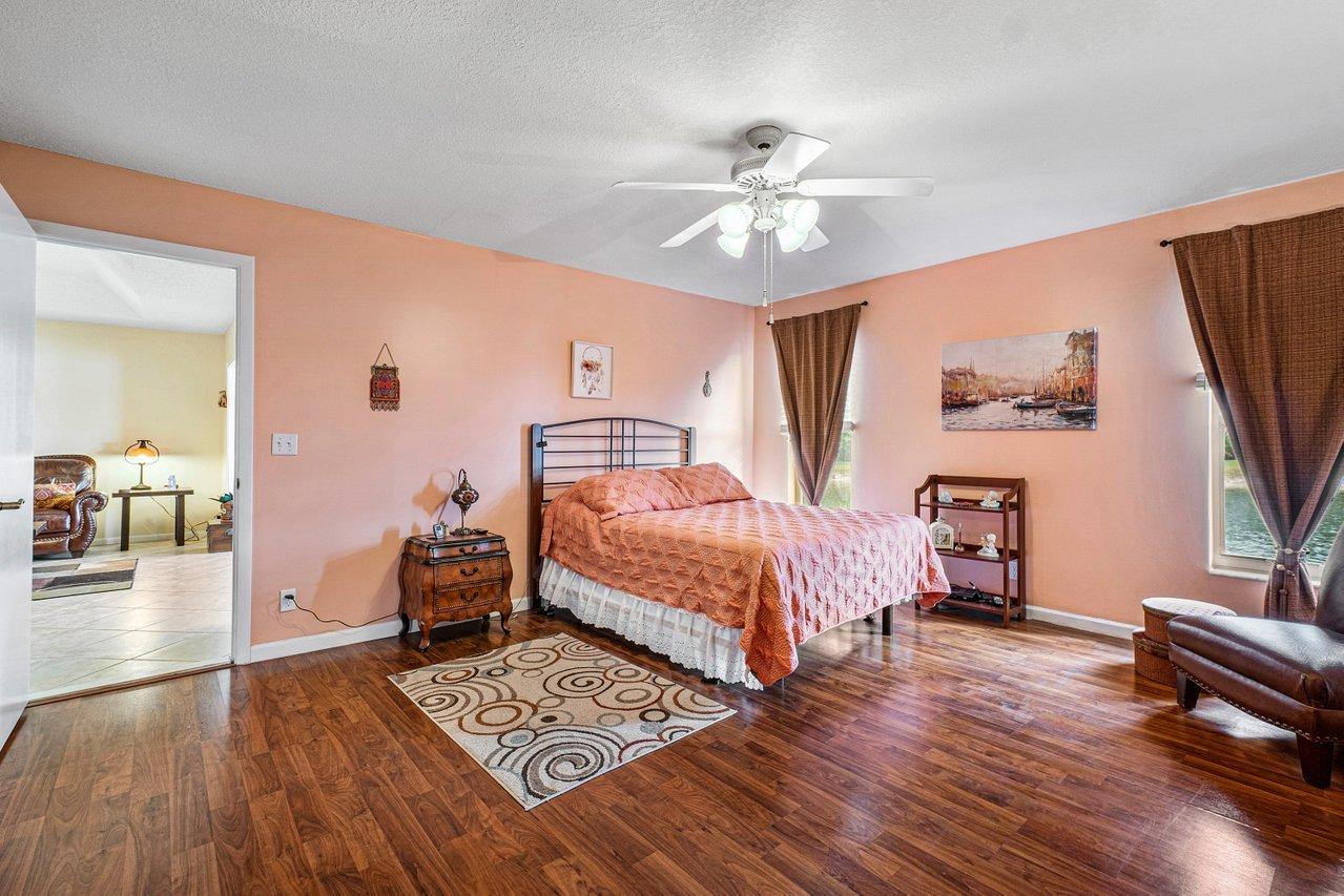 9155 Pine Springs Drive Boca Raton, FL 33428 - Photo 15 of 24 a bedroom with a bed and wooden floor