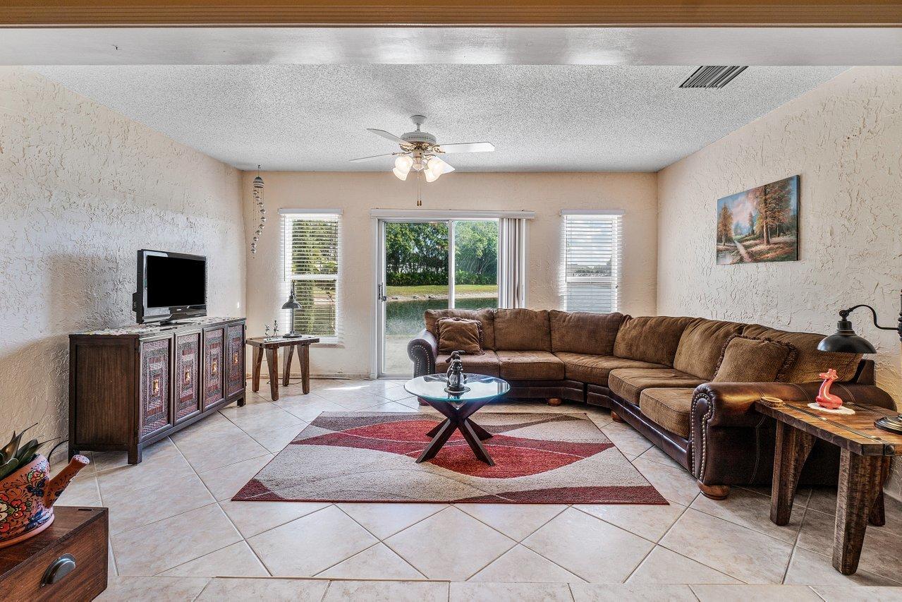 9155 Pine Springs Drive Boca Raton, FL 33428 - Photo 5 of 24 a living room with furniture a flat screen tv and a floor to ceiling window