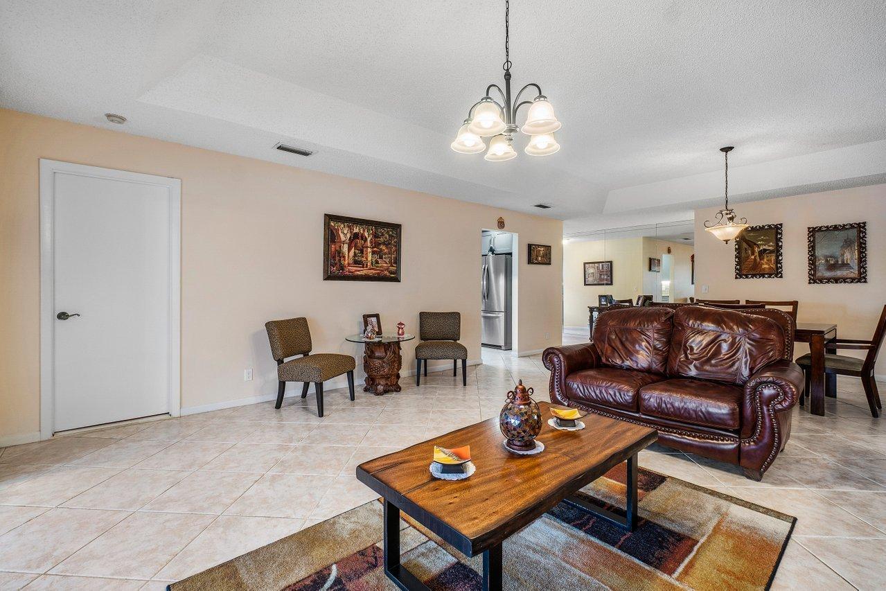 9155 Pine Springs Drive Boca Raton, FL 33428 - Photo 8 of 24 a living room with furniture a table and a chandelier