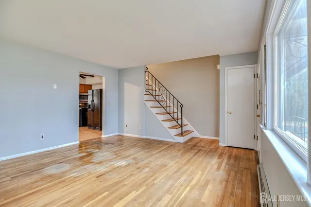 a view of an empty room with wooden floor and stairs