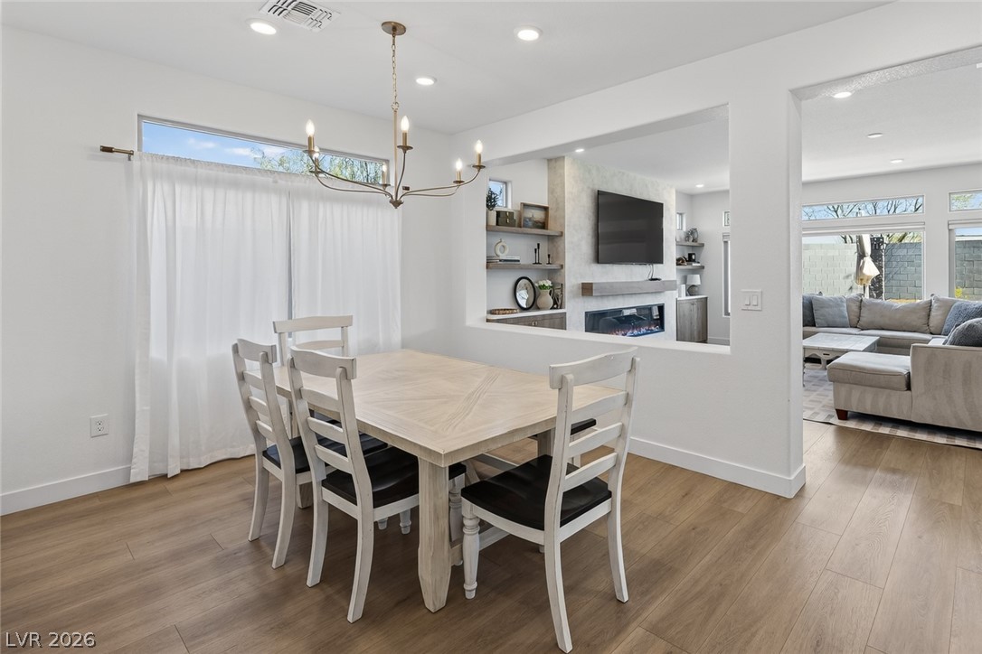 10446 Emerald Rye Street Las Vegas, NV 89183 - Photo 7 of 37 A well-lit dining area featuring rich hardwood floors and an elegant chandelier.