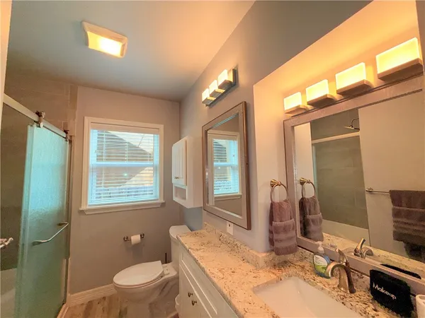 a bathroom with a granite countertop toilet a sink and a mirror