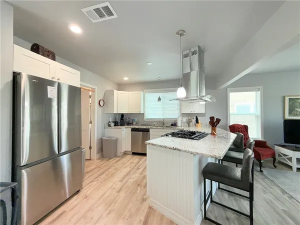 a kitchen with a refrigerator a stove cabinets dining table and chairs