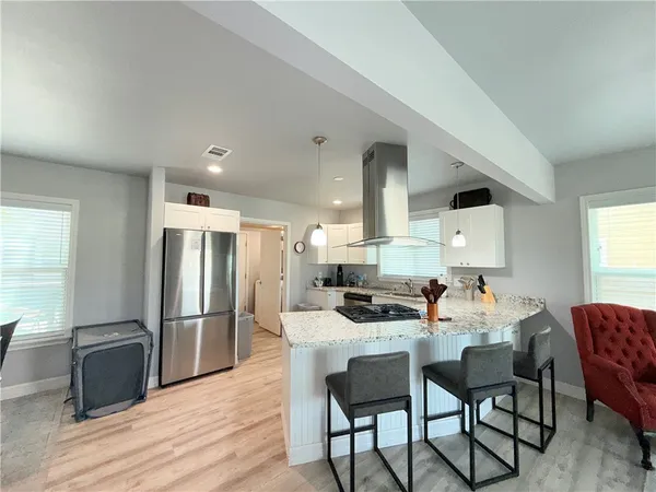 a kitchen with stainless steel appliances kitchen island granite countertop a dining table chairs and a refrigerator