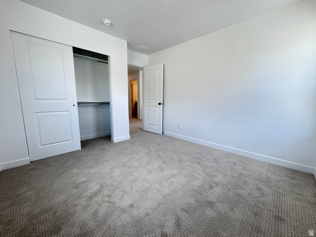 2633 Scarlet Road, Unit 259 Eagle Mountain, UT 84005 - Photo 22 of 30 Bedroom featuring wall-to-wall carpeting, white painted walls, white baseboards, and a closet with sliding panel doors