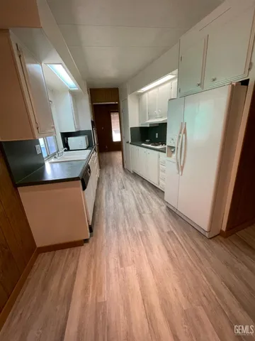 a large white kitchen with a large window a sink and a counter top space