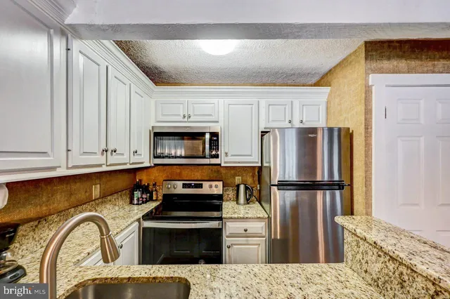 a kitchen with stainless steel appliances granite countertop a refrigerator sink and stove