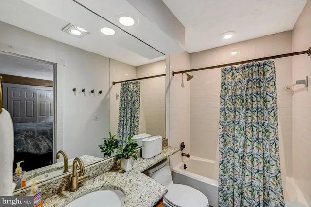 a bathroom with a granite countertop sink a toilet and a mirror