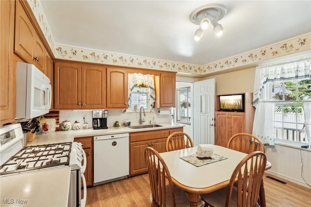 10818 Dixon Road Cleveland, OH 44111 - Photo 20 of 44 Kitchen with white appliances, light countertops, light wood-style flooring, tasteful backsplash, and brown cabinets