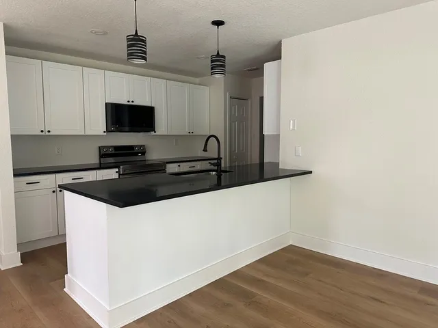 a kitchen with a sink a microwave and wooden floor