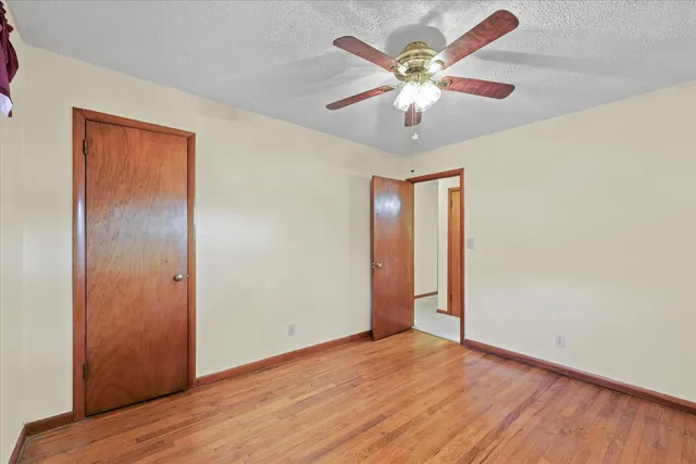 an empty room with wooden floor and a ceiling fan