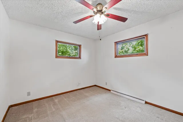 an empty room with windows and fan