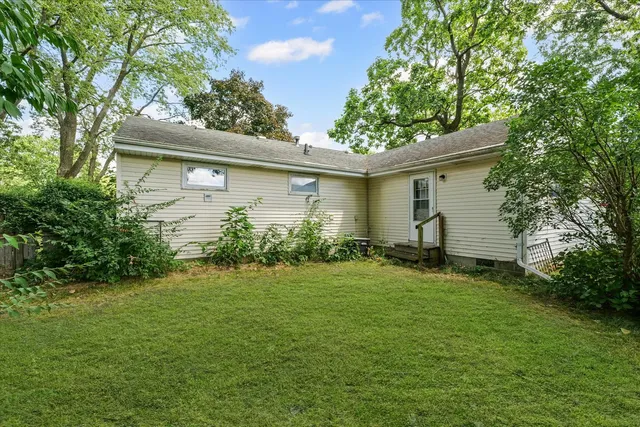 a backyard of a house with plants and large tree