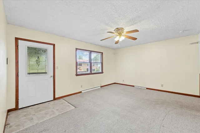an empty room with chandelier fan and windows