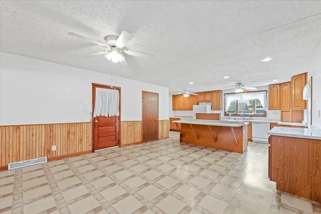 a open kitchen with stainless steel appliances granite countertop a refrigerator a sink dishwasher and a stove with wooden cabinets