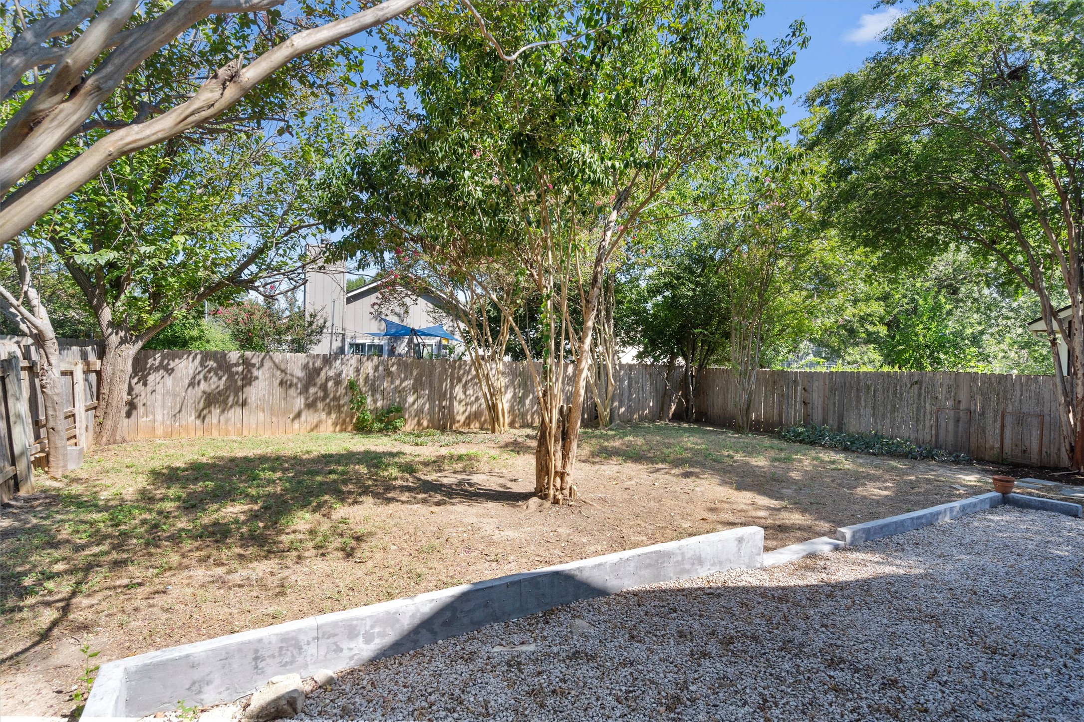 12321 Emery Oaks Road Austin, TX 78758 - Photo 27 of 27 Secure yard featuring a wooden privacy fence, mature trees, and a terraced gravel area.