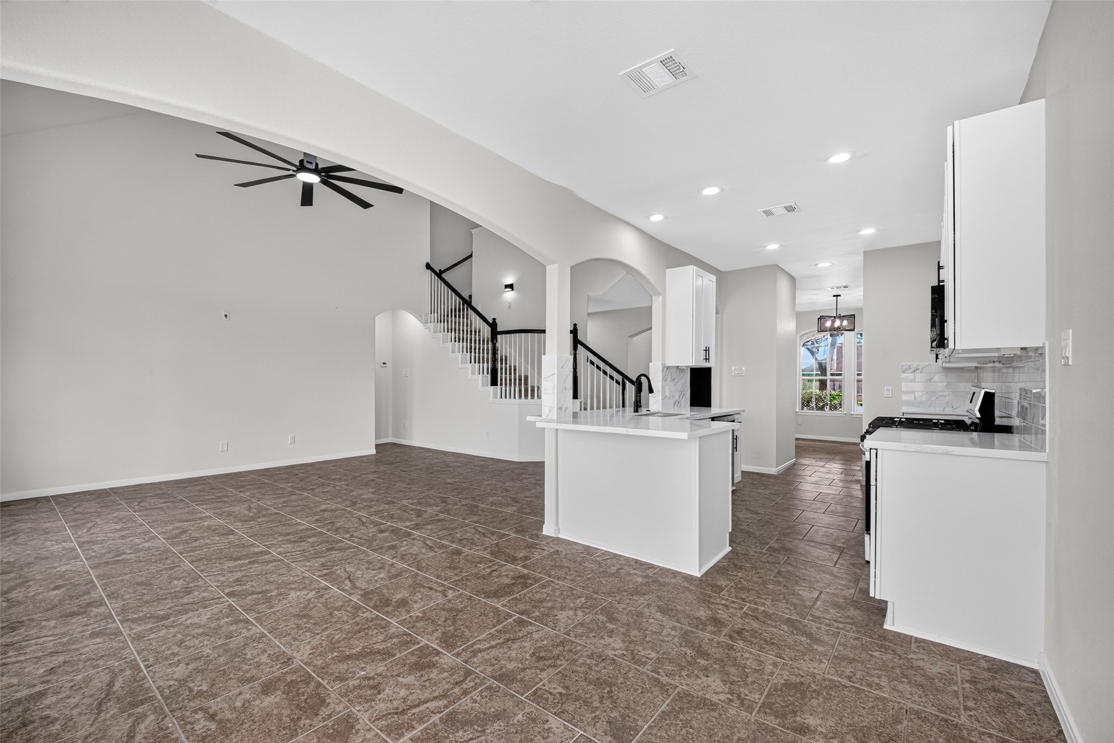 22623 Ebbets Field Drive Spring, TX 77389 - Photo 15 of 43 The ultimate heart of the home, this open-concept living space effortlessly connects everyday lounging with culinary creation. High ceilings and sleek, gleaming tile floors frame the modern kitchen—where crisp white cabinetry meets high-end stainless steel appliances—creating a bright, fluid environment made for entertaining and easy living.