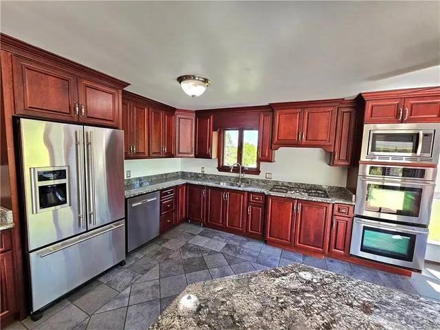 a kitchen with stainless steel appliances granite countertop a refrigerator a stove and a sink