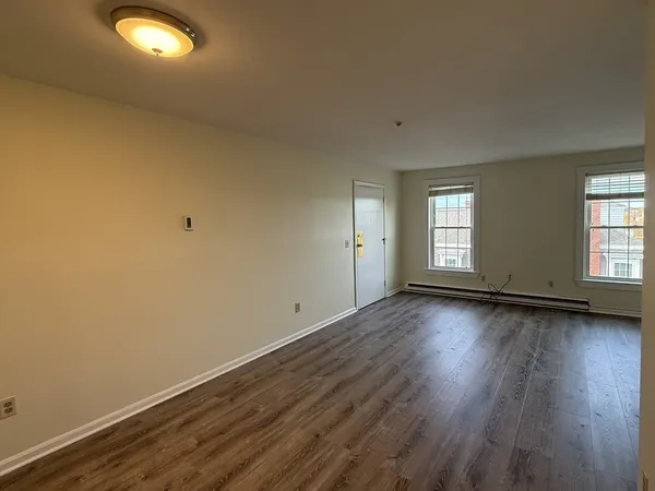 an empty room with wooden floor and windows