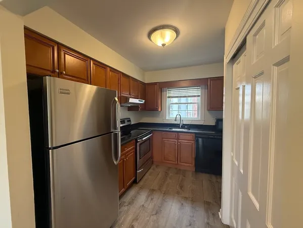 a kitchen with a refrigerator a stove top oven and wooden floor