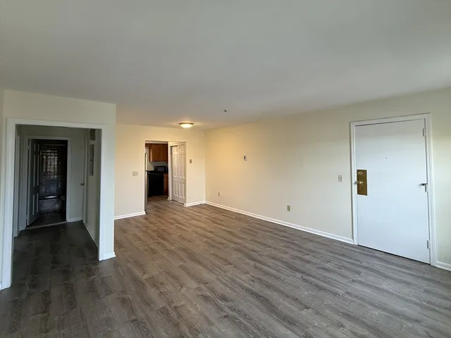 a view of an empty room with wooden floor and closet