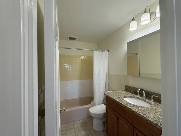 a bathroom with a granite countertop sink toilet and shower
