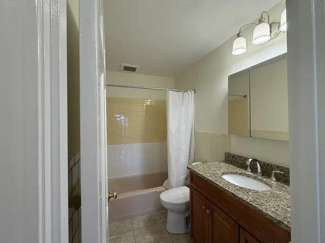a bathroom with a granite countertop sink toilet and shower