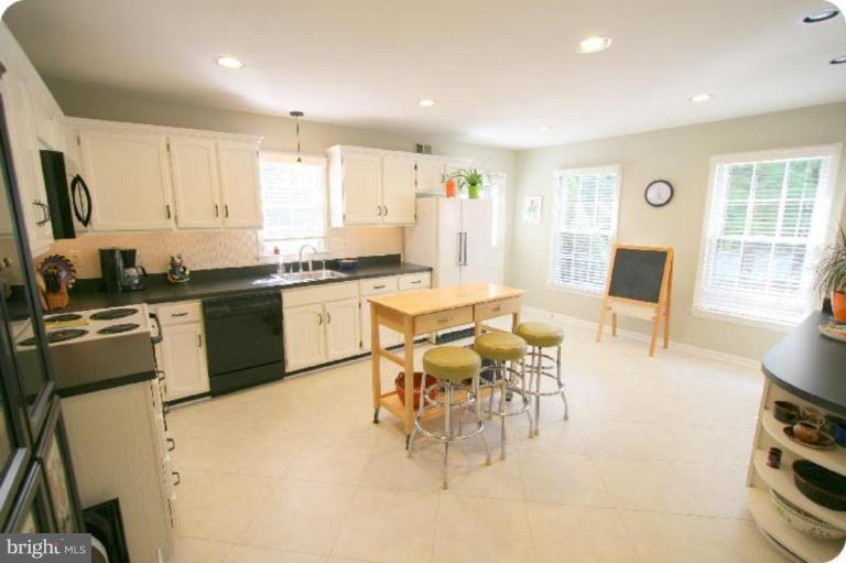 10915 Hunt Club Road Reston, VA 20190 - Photo 6 of 27 a kitchen with stainless steel appliances granite countertop a stove top oven a sink a dining table and chairs with wooden floor