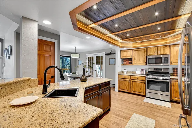 a kitchen with stainless steel appliances granite countertop a stove top oven a sink a dining table and chairs