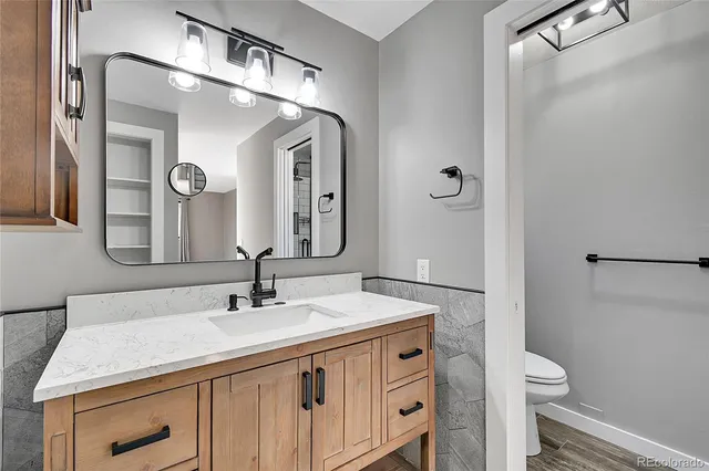 a bathroom with a granite countertop sink a toilet and a mirror