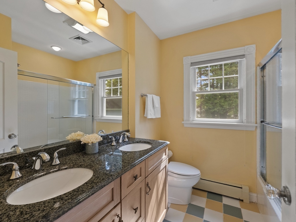 22 Bryant Road Lexington, MA 02420 - Photo 29 of 40 a bathroom with a granite countertop sink a toilet a mirror and shower