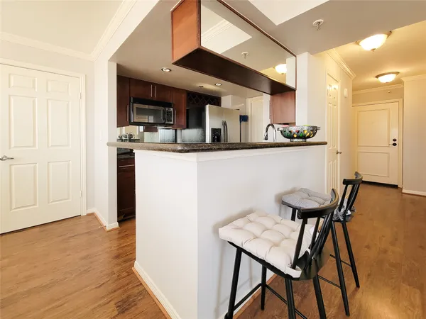a kitchen with stainless steel appliances kitchen island granite countertop a table chairs in it and wooden floors