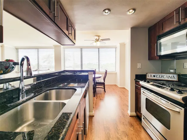 a kitchen with kitchen island granite countertop a stove and a sink
