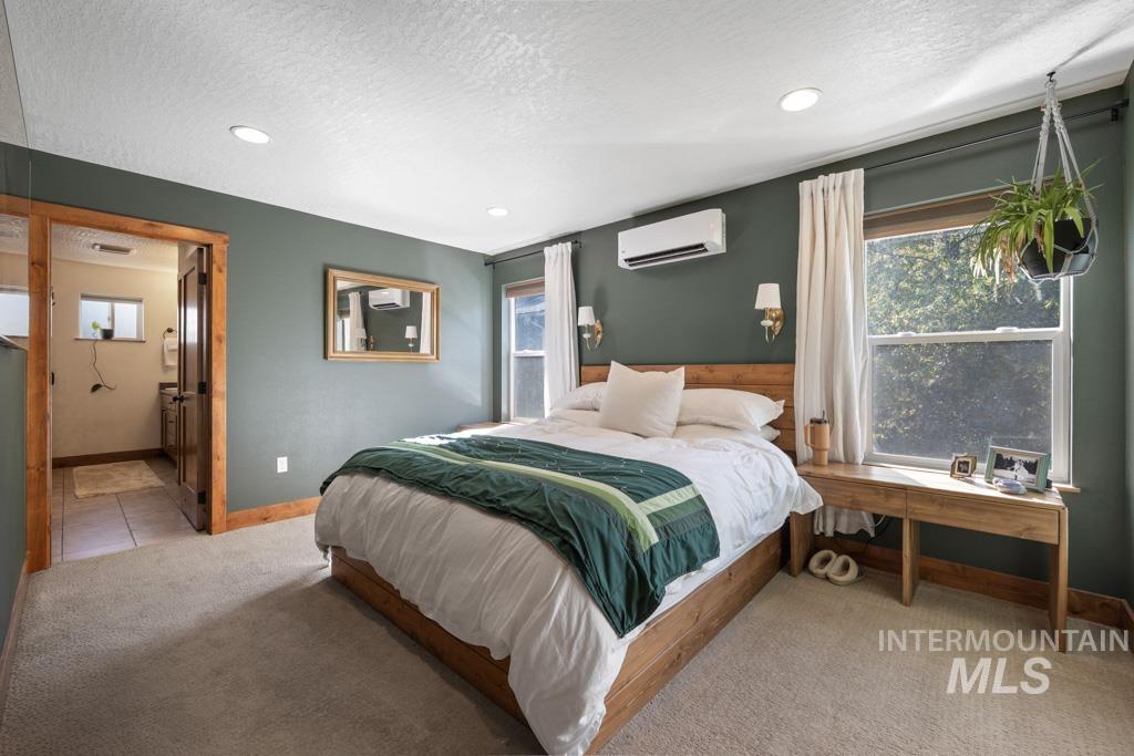 417 East E Street Moscow, ID 83843 - Photo 15 of 29 Bedroom featuring a textured ceiling, carpet, ensuite bathroom, an AC wall unit, and recessed lighting