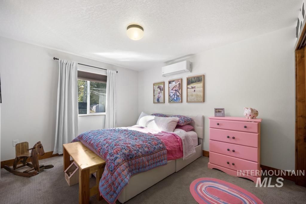 417 East E Street Moscow, ID 83843 - Photo 17 of 29 Bedroom featuring a textured ceiling, carpet floors, and an AC wall unit