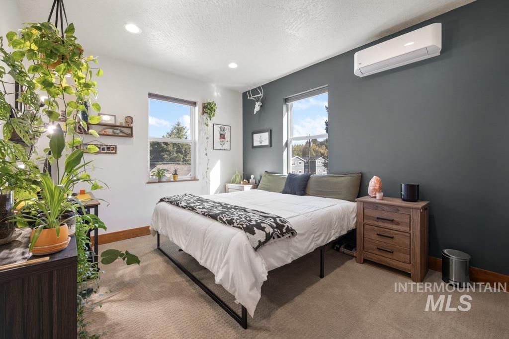 417 East E Street Moscow, ID 83843 - Photo 23 of 29 Carpeted bedroom with multiple windows, a wall unit AC, a textured ceiling, and recessed lighting