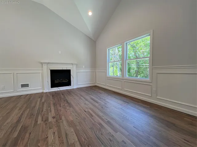 an empty room with wooden floor a fireplace and windows