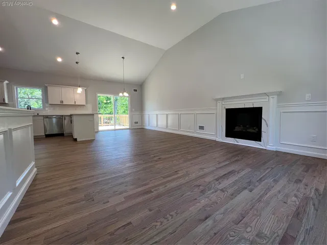 a view of a kitchen and an empty room with wooden floor and a kitchen